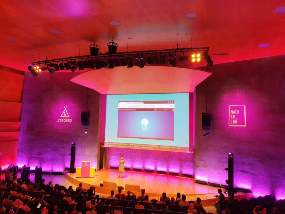 Megha on stage at CSS camp in barcelona. Screen behind her shows an SVG jellyfish.